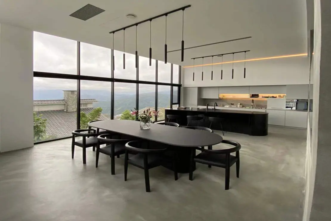 Comedor con diseño abierto hacia la cocina con piso de microcemento.
